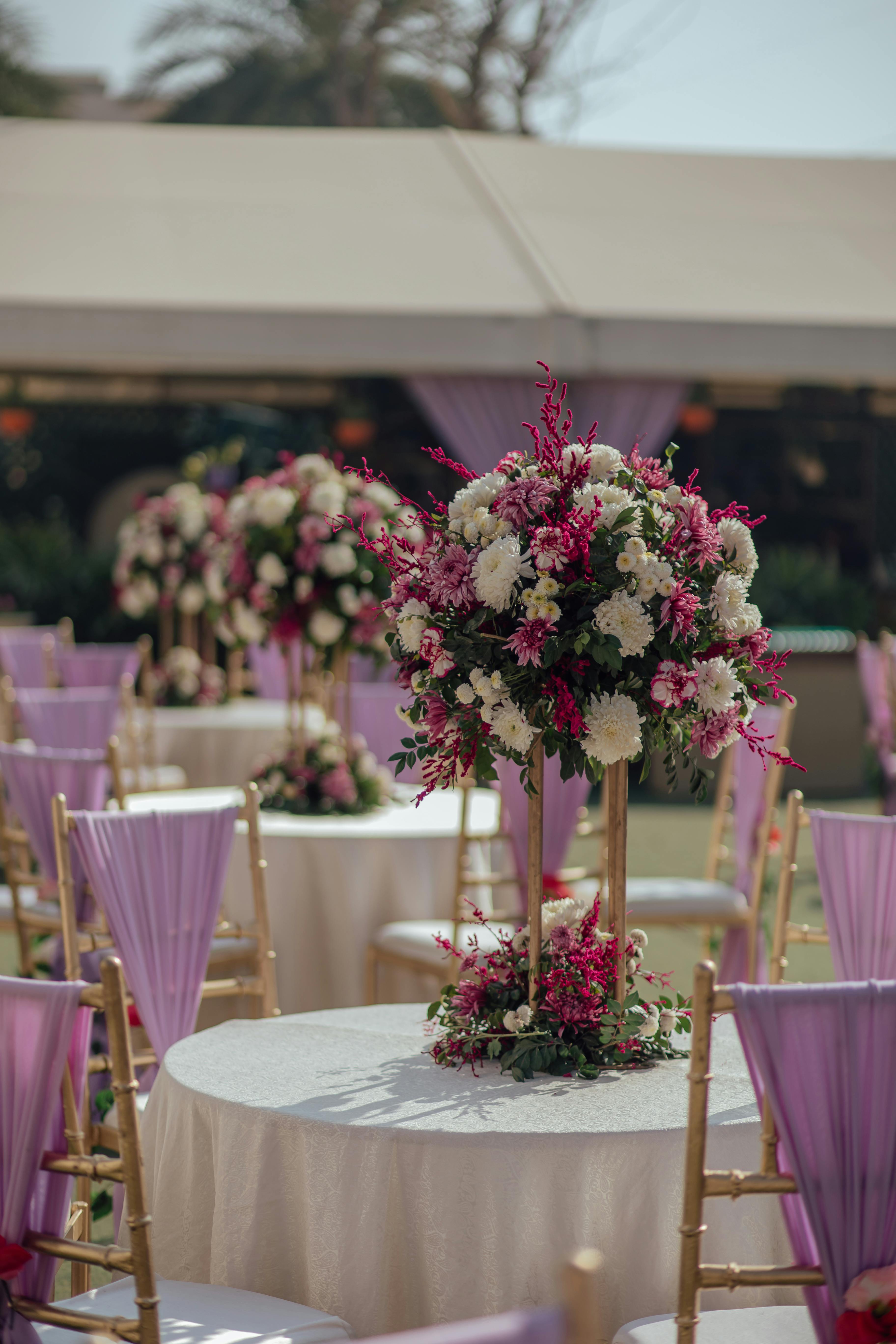 Chic wedding setup with floral centerpiece and lavender chairs outdoors.